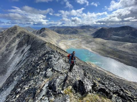 Geologist overlooking a mountain lake from a ridge top at the Findlay property