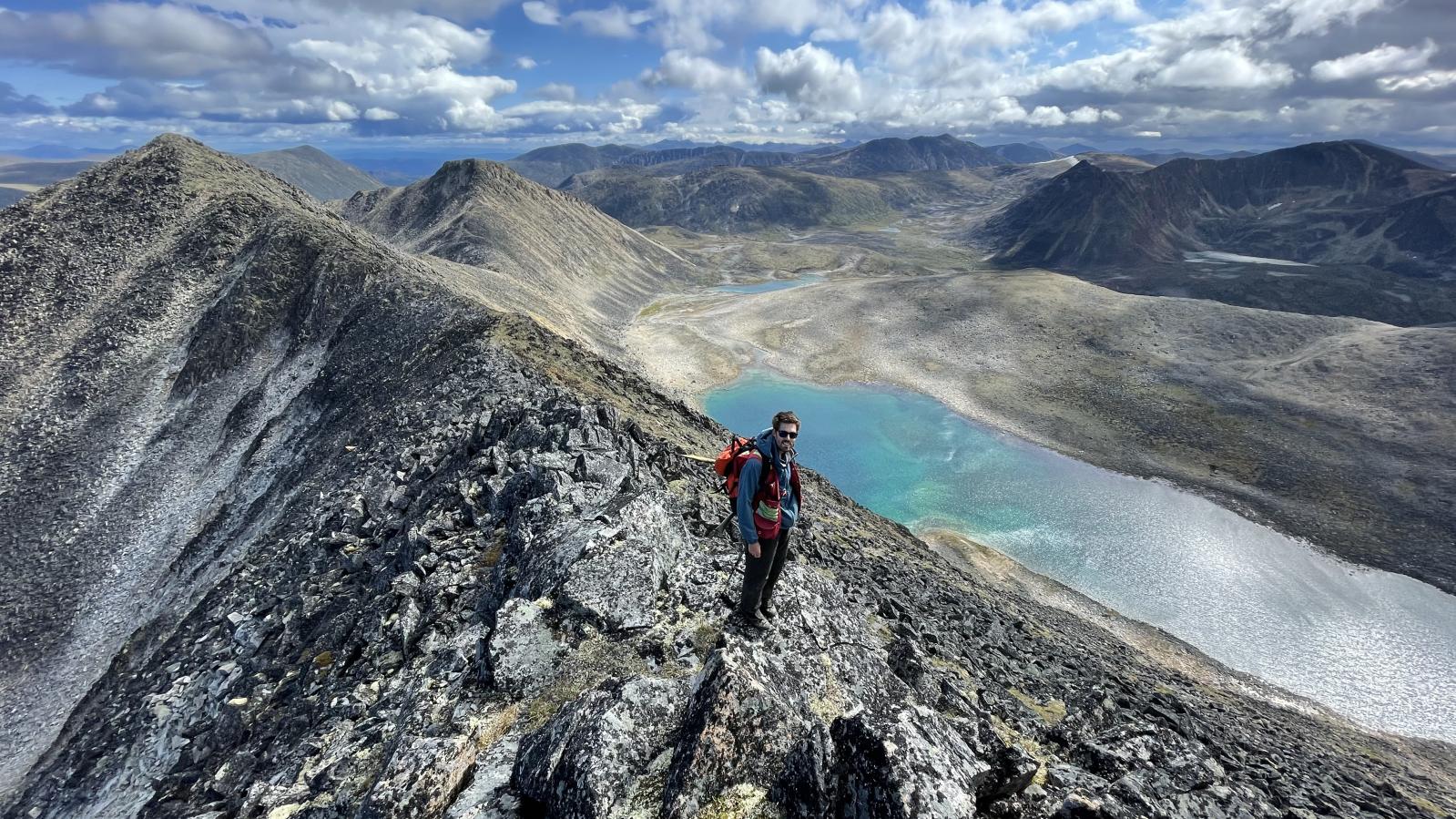 Geologist overlooking a mountain lake from a ridge top at the Findlay property
