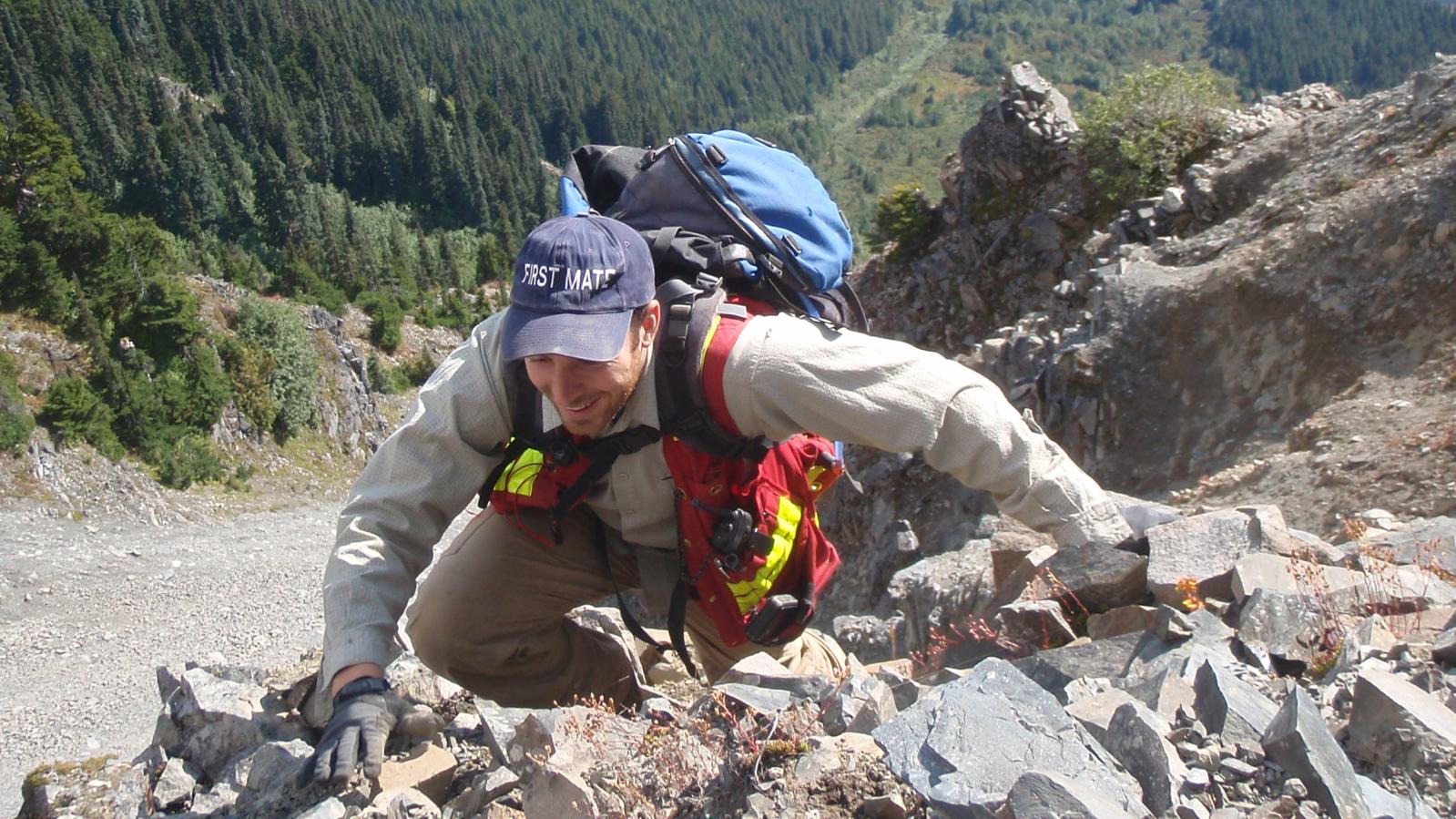 Exploration crew member climbing a very steep slope in northwest BC