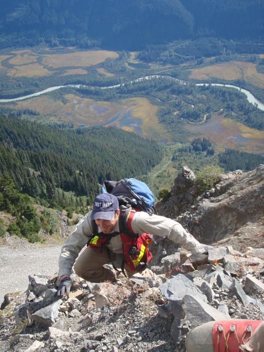 Exploration crew member climbing a very steep slope in northwest BC